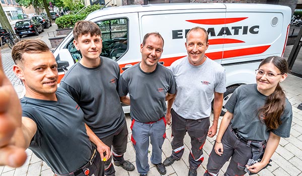 Selfie-Bild mehrerer Mitarbeitender vor Firmenwagen